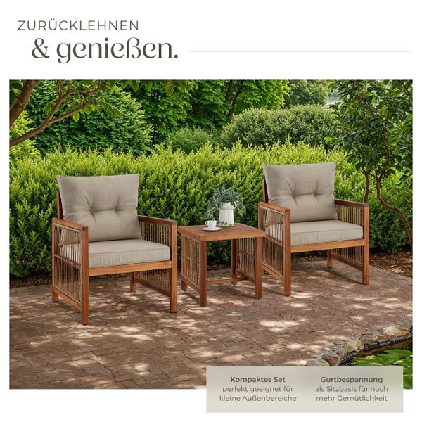 Kompaktes Gartenmöbel-Set aus Holz mit zwei Sesseln inklusive Polstern und einem Beistelltisch auf einer gepflasterten Terrasse im Garten.