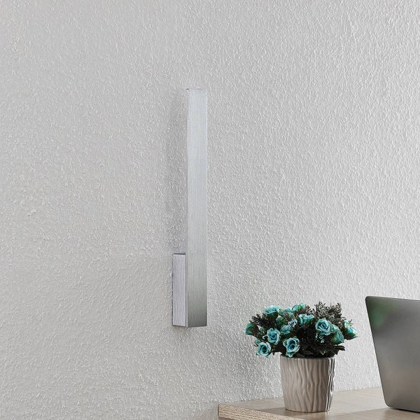 Moderne vertikale Wandleuchte aus gebürstetem Metall an einer strukturierten Wand über einem Schreibtisch.