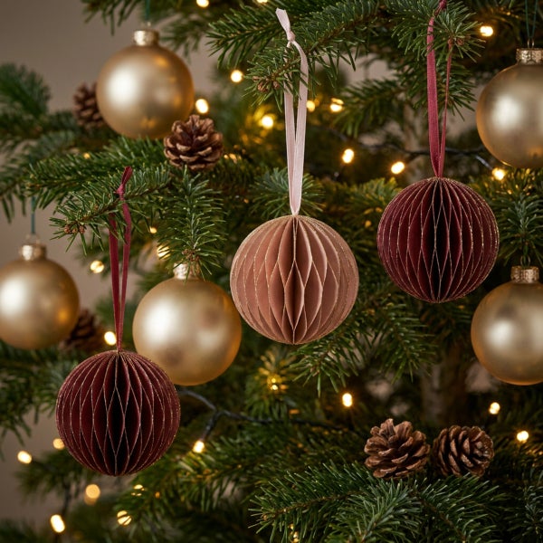 Weihnachtsbaum mit Anhängern aus Papierwaben, glänzenden Kugeln und Tannenzapfen, stimmungsvolle Weihnachtsdekoration am Tannenbaum.