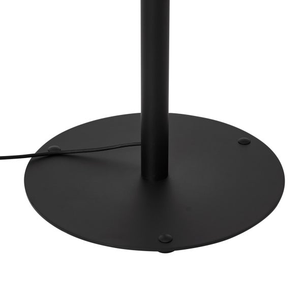 Schwarzer runder Standfuß einer Stehlampe aus Metall inklusive Kabel.