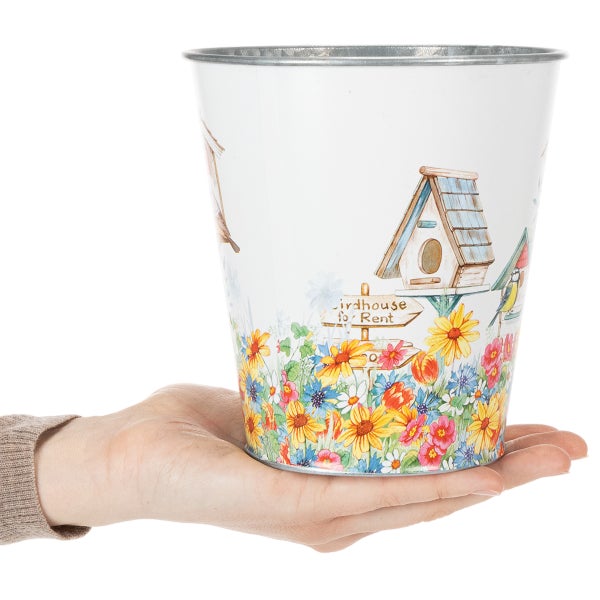Dekorativer Metall-Blumentopf mit Vogelhaus- und Blumenmotiv, in einer Hand gehalten zur Größendarstellung.