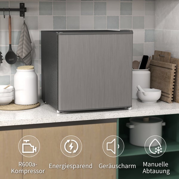 Mini-Kühlschrank in gebürsteter Metalloptik auf Küchenplatte. Symbole für Kompressor, Energiesparen, Geräuscharmut und manuelle Abtauung.