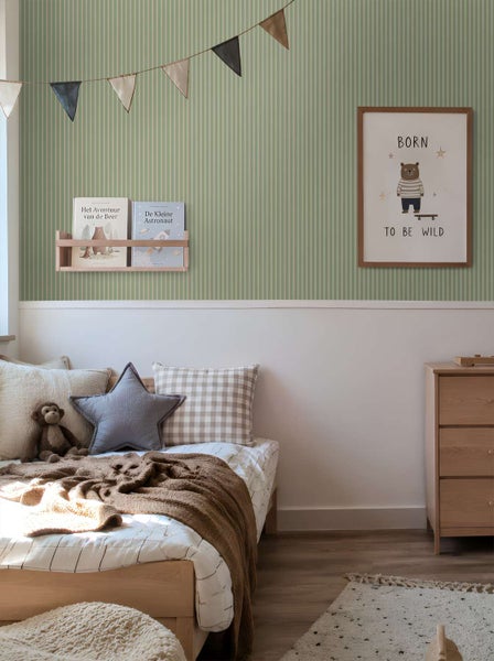 Kinderzimmer mit gestreifter Tapete in dezentem Design, dekoriert mit Wimpelkette, Bilderrahmen und Bücherregal über einem Kinderbett.