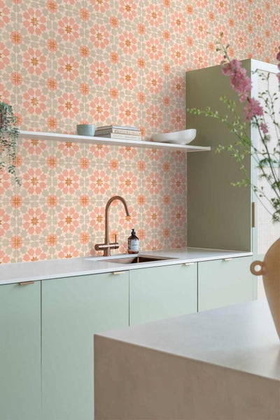 Moderne Küche mit geometrischer Mustertapete in Sternform, hellgrünen Schränken, weißer Arbeitsplatte und kupferfarbenem Wasserhahn.
