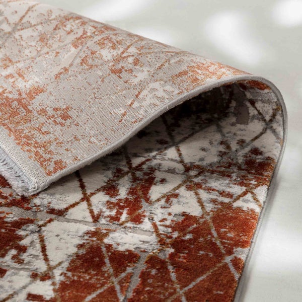 Nahaufnahme eines Teppichs mit abstraktem geometrischem Muster und umgeschlagener Ecke zur Ansicht der Rückseite.