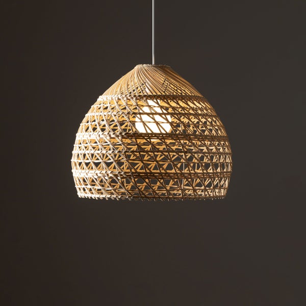 Pendelleuchte aus geflochtenem Rattan in Glockenform mit eingeschaltetem Leuchtmittel.