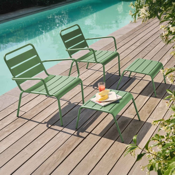 Garten-Lounge-Möbel aus grünem Metall auf einer Holzterrasse neben einem Pool, bestehend aus zwei Sesseln und zwei Beistelltischen.