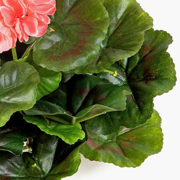 Nahaufnahme einer künstlichen Geranie mit strukturierten grünen Blättern und einer rosa Blüte.