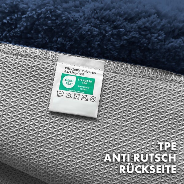 Detailansicht eines Teppichs mit Etikett, das die Materialzusammensetzung (100 Prozent Polyester Flor, TPE Rückseite) und Pflegehinweise angibt, inklusive Oeko-Tex Standard 100 Siegel.