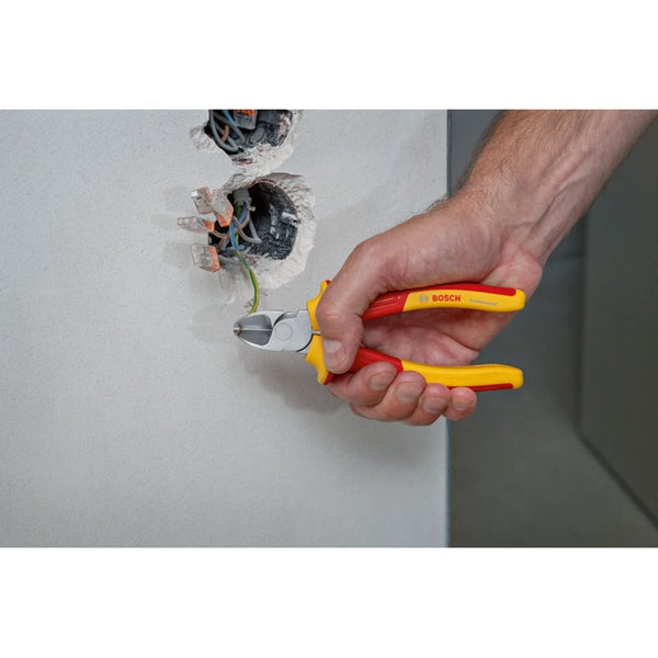 Ein Bosch Professional Seitenschneider wird verwendet, um ein elektrisches Kabel in einer Wanddose zu kürzen.