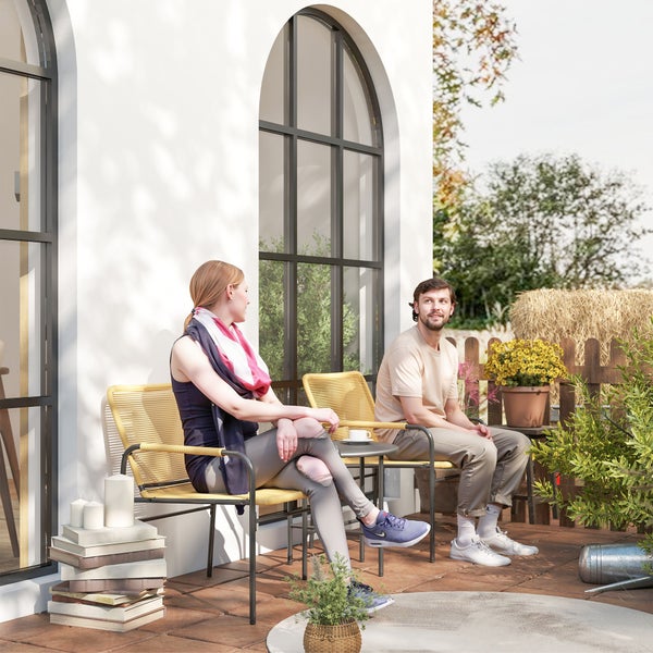 Terrassenszene mit zwei Personen auf Korbsesseln an einem Tisch, dekoriert mit Pflanzen und Büchern
