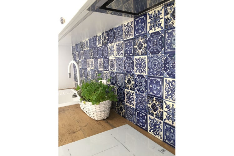 Küchenszene mit blau-weißen Fliesen, Spüle und Kräutern im Korb