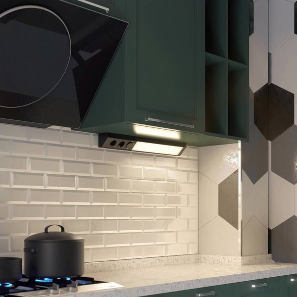 Unterbauleuchte mit integrierten Steckdosen unter einem grünen Küchenschrank montiert, beleuchtet einen weißen Fliesenspiegel in einer modernen Küche.