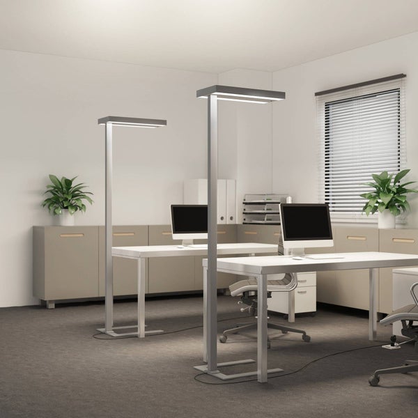 Zwei moderne LED Stehleuchten aus Metall in einem hellen, organisierten Büro mit weißen Schreibtischen und Monitoren.