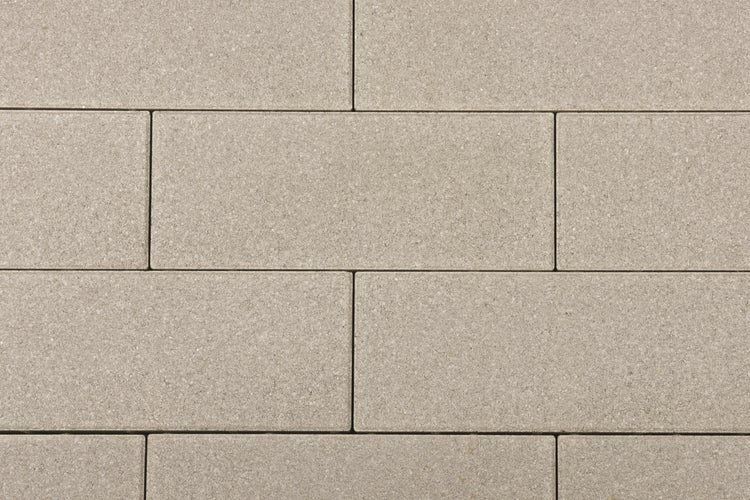 Rechteckige Pflastersteine aus Beton in versetzter Anordnung mit strukturierter Oberfläche.