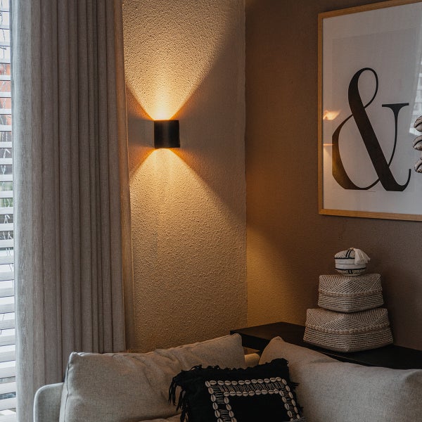 Wohnzimmer-Szene mit Wandleuchte, Sofa und Dekorationen für eine gemütliche Atmosphäre