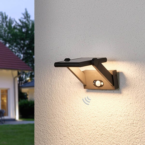 Solarbetriebene LED-Wandleuchte mit Bewegungsmelder an einer Außenwand montiert, Lichtkegel nach unten gerichtet.