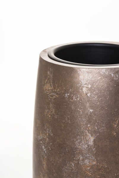 Nahaufnahme eines Pflanzkübels mit strukturierter, metallic-brauner Oberfläche und dunkler Innenseite.