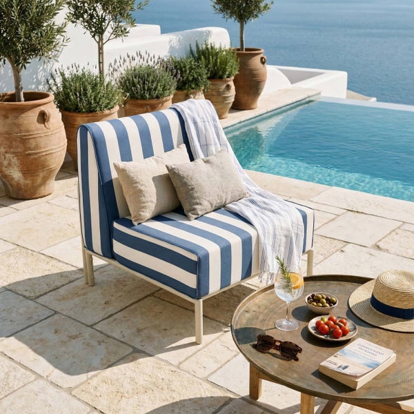 Gestreifter Outdoor-Sessel mit blau-weißen Polstern auf einer Steinterrasse am Pool mit Meerblick und Terrakotta-Töpfen.