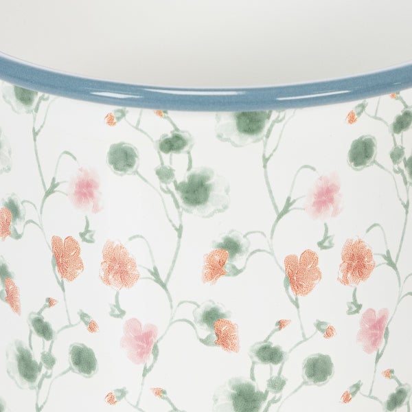 Detailansicht einer weißen Emaille-Schale mit floralem Muster und blauem Rand.