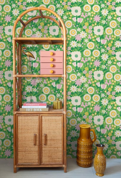 Retro-Vliestapete mit floralem Blumenmuster an einer Wand, davor steht ein Bambusregal mit Dekorationsartikeln und Keramikvasen.