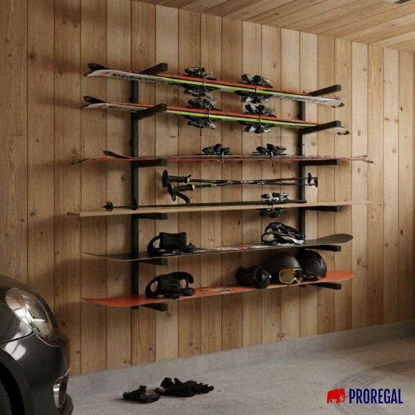 Schwarzes Wandregal aus Metall für Skier und Snowboards an einer Holzwand. Organisierte Lagerung in einer hellen Garage. Proregal Logo.
