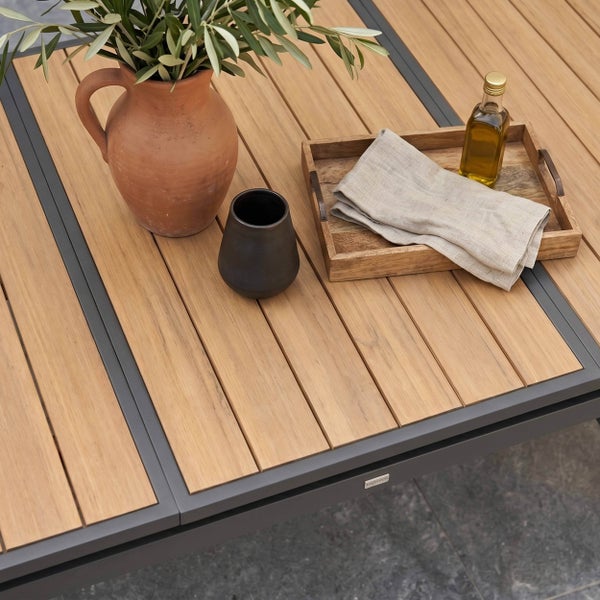Gartentisch mit Tischplatte aus Holzlatten und Metallrahmen, dekoriert mit Krug aus Terrakotta, Tasse und Holztablett.