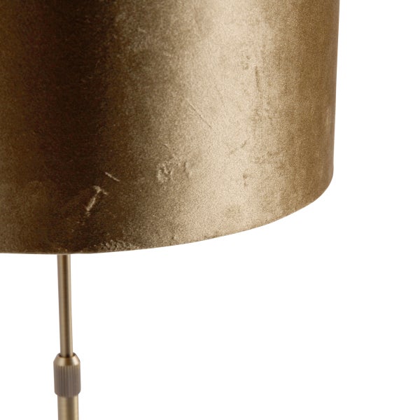 Nahaufnahme einer Tischleuchte mit zylindrischem Lampenschirm aus strukturiertem goldfarbenem Stoff auf einem Metallstab.