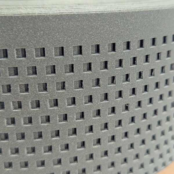 Detailaufnahme einer perforierten Metallplatte mit quadratischen Aussparungen