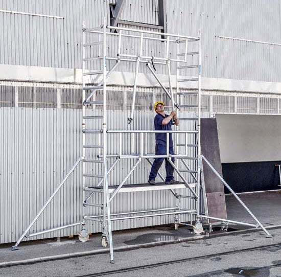 Fahrgerüst mit Arbeiter in Arbeitskleidung und Schutzhelm