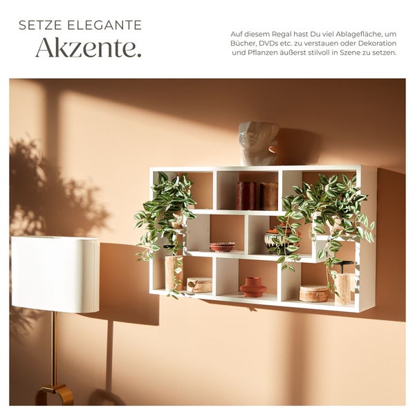 Modernes weißes Wandregal mit asymmetrischen Fächern, dekoriert mit Zimmerpflanzen, Vasen und Holzobjekten.