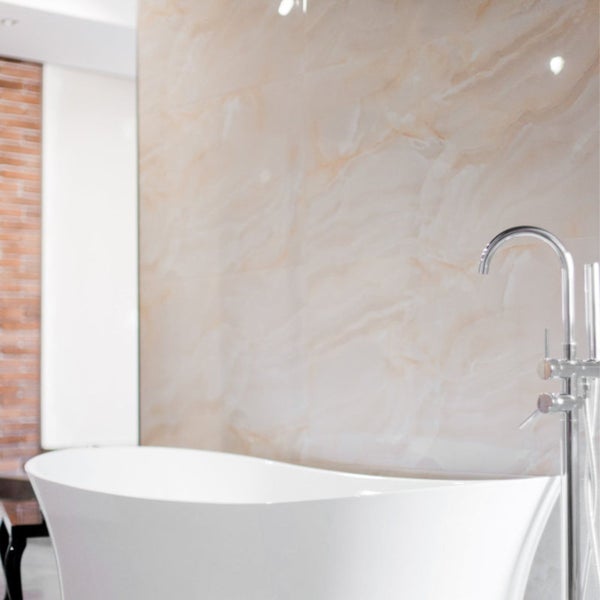 Freistehende Badewanne mit Armatur vor einer Wand in Marmoroptik