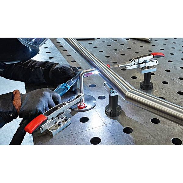 Schweißer bei der Arbeit an einem Metallrohr mit Schweißtisch und Spannwerkzeugen