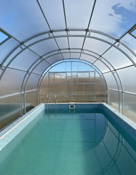 Überdachtes Schwimmbecken mit einer bogenförmigen Poolüberdachung aus Kunststoffplatten und Metallrahmen in einem hellen, offenen Gartenbereich.