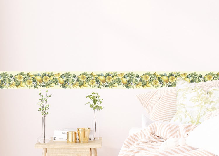 Tapetenborte mit Zitronen- und Blättermotiv an einer Wand im Schlafzimmer über einem Nachttisch mit dekorativen Vasen und Büchern.