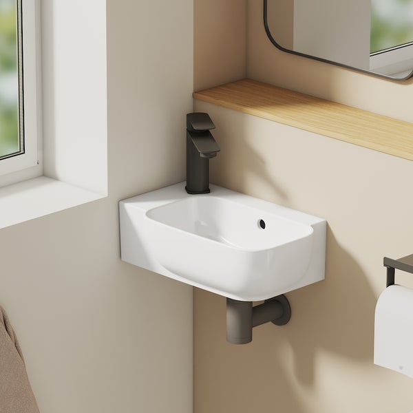 Detailansicht eines weißen Waschbeckens mit dunkler Armatur und Holzablage im Badezimmer