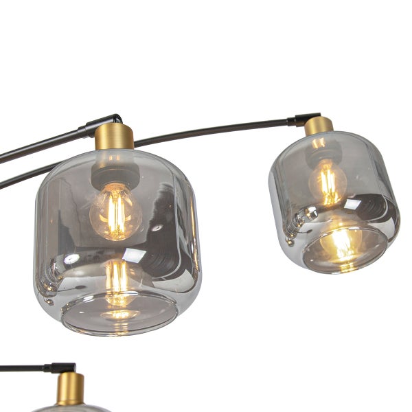 Nahaufnahme einer Deckenleuchte mit Schirmen aus rauchgrauem Glas, goldfarbenen Fassungen und Filament-Leuchtmitteln an schwarzen Metallarmen.