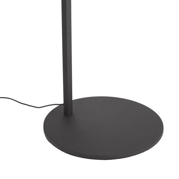 Schwarzer runder Sockel einer Stehleuchte mit eckigem Standrohr und Kabel.