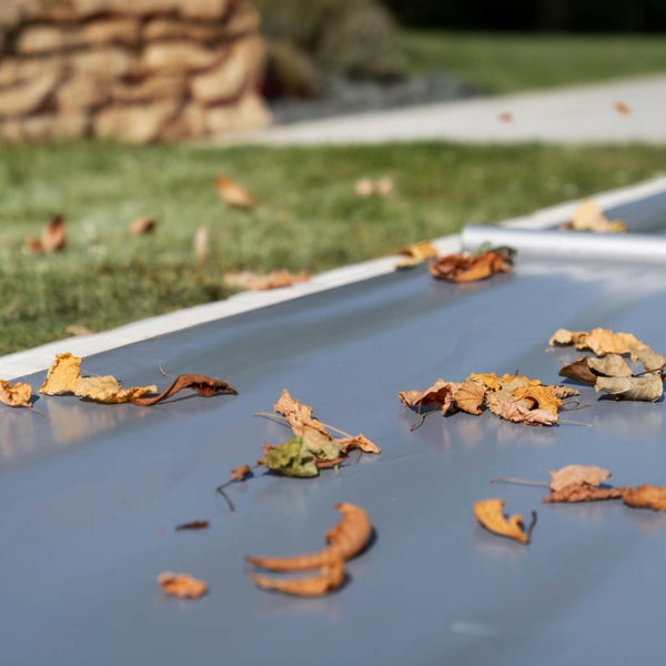 Detailaufnahme einer Poolabdeckung mit Herbstlaub