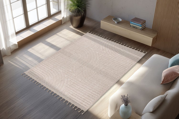 Wohnzimmer mit rechteckigem gewebtem Teppich mit Fransen und geometrischem Muster auf Parkettboden neben Sofa und Holzregal.