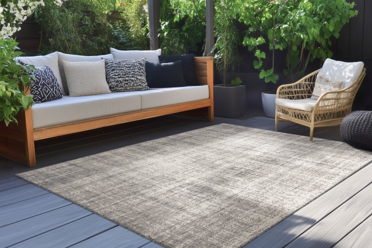 Ein moderner Outdoor-Teppich mit dezenter Textur auf einer Terrasse mit Gartenmöbeln aus Holz und Rattan in einer ansprechenden Gartenumgebung.