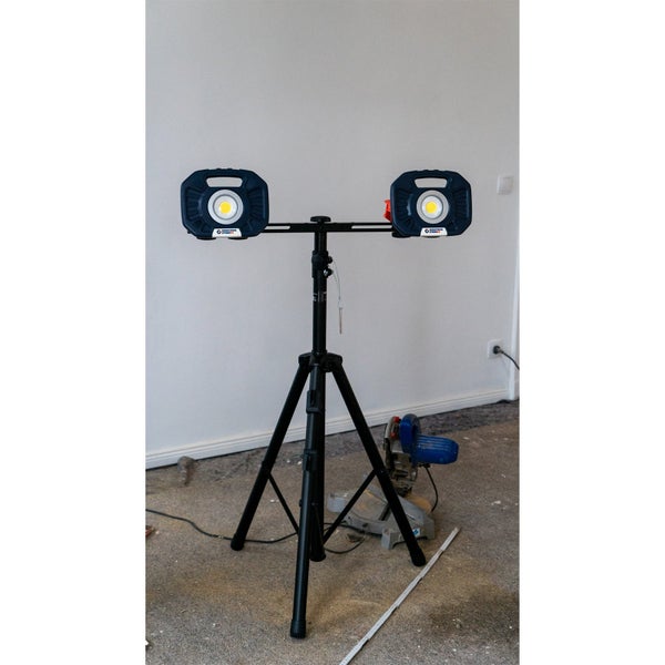 Zwei LED-Arbeitsstrahler auf einem schwarzen, höhenverstellbaren Stativ in einem hellen, organisierten Raum während einer Renovierung.