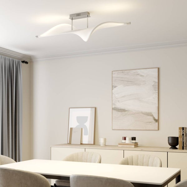 Moderne wellenförmige LED Deckenleuchte in einem hellen modern eingerichteten Esszimmer mit weißem Tisch und Sideboard