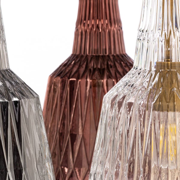 Nahaufnahme von drei Pendelleuchtenschirmen aus strukturiertem, facettiertem Glas in verschiedenen Farben mit geometrischem Rautenmuster.