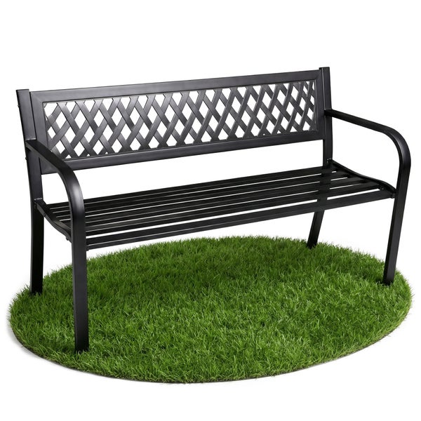 Familie in einem hellen, modernen Garten. Die Eltern sitzen auf einer schwarzen Gartenbank aus Metall mit dekorativer Rückenlehne.