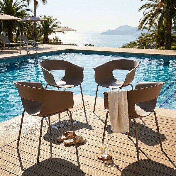 Vier moderne Gartenstühle mit Aussparung auf einer Holzterrasse an einem Pool mit Palmen und Meerblick.