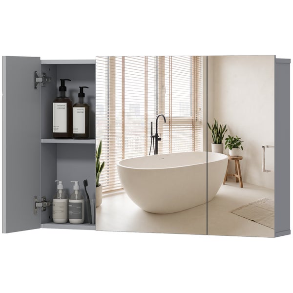 Dreitüriger Spiegelschrank fürs Bad, eine Tür geöffnet mit Glasböden und Produkten, spiegelt ein helles Badezimmer mit freistehender Badewanne.