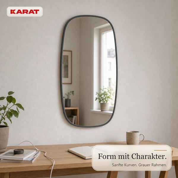 Ovaler Wandspiegel mit schmalem Rahmen montiert über einem Schreibtisch aus Holz, Karat Logo.