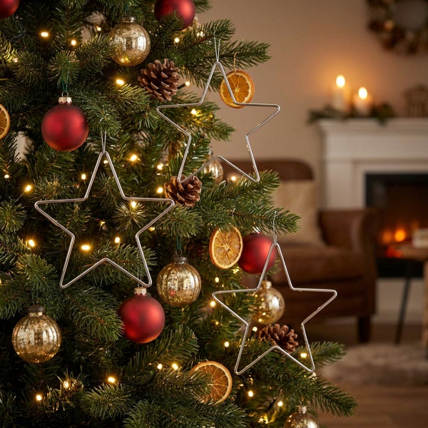 Geschmückter Weihnachtsbaum mit silbernen Sternanhängern, Weihnachtskugeln, getrockneten Orangenscheiben und Tannenzapfen in einem gemütlichen Raum.