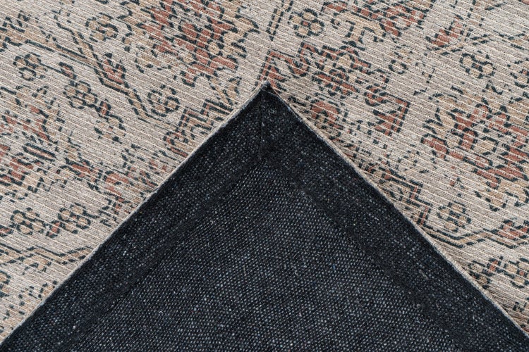 Teppich mit Orient-Muster im Vintage-Stil und umgeknickter Ecke zur Ansicht der rutschhemmenden Rückseite.